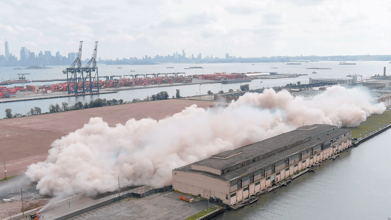 Following a series of loud bangs, two buildings at the former Military Ocean Terminal in Bayonne, New Jersey, were imploded to the cheers of onlookers, leaving a cloud of dust. (Todd Plitt/Lincoln Equities Group) 