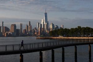 The sun rises on the skyline of lower Manhattan and One World Trade Center in New York City as a person walks on a pier in the Hudson River on June 9, 2023, in Hoboken, New Jersey.  (Getty Images)