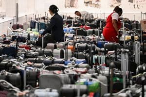 Delta employees look through bags awaiting reunification with their owners in the Delta Air Lines baggage claim area Los Angeles International Airport (LAX) on July 24. The United States Department of Transportation (USDOT) announced an investigation into Delta Air Lines to comply with passenger protection laws following the CrowdStrike global software outage that disrupted airlines, banks, TV channels and other businesses worldwide. (Getty Images)